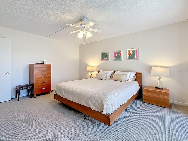 bedroom with baseboards, light colored carpet, a textured ceiling, and a ceiling fan