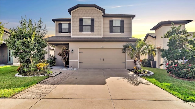 view of front facade with a yard, a garage, concrete driveway, and stucco siding