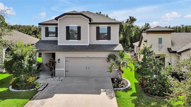 view of front of home with concrete driveway, a front yard, and a shingled roof