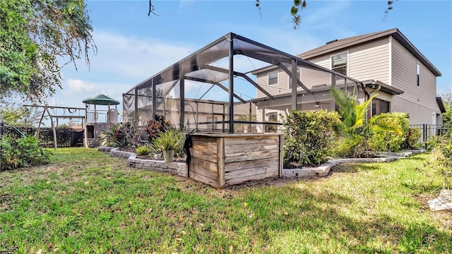 rear view of house featuring glass enclosure, a yard, and a ceiling fan