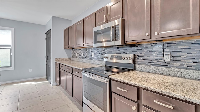 kitchen with light tile patterned floors, stainless steel appliances, light stone counters, and tasteful backsplash