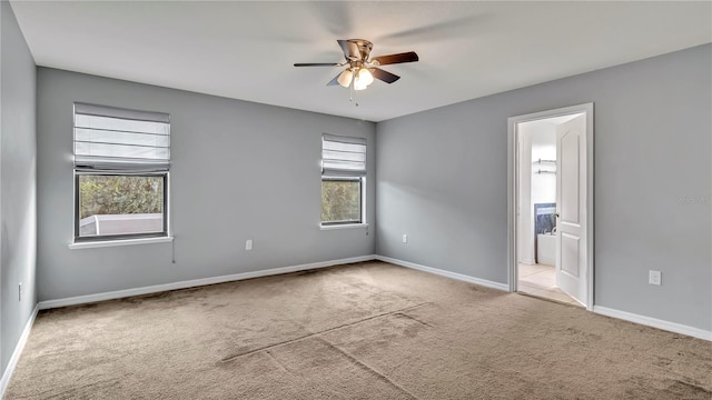 carpeted spare room with a ceiling fan and baseboards