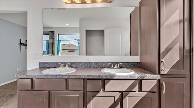 full bathroom with double vanity, baseboards, visible vents, and a sink