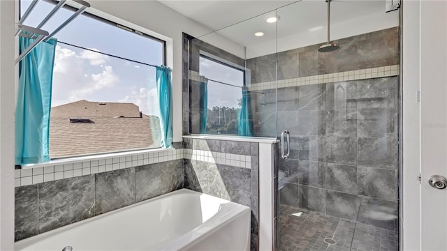 bathroom featuring a bath, a healthy amount of sunlight, and a stall shower