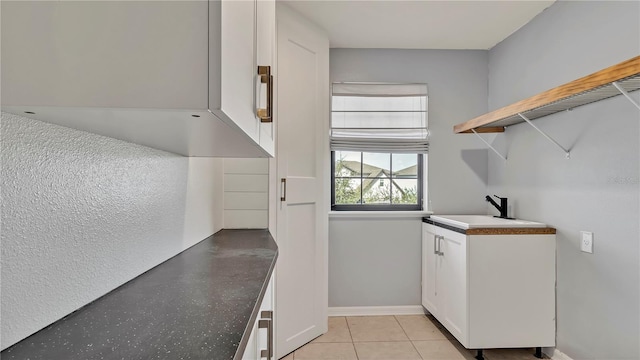 laundry area with light tile patterned floors, baseboards, and a sink