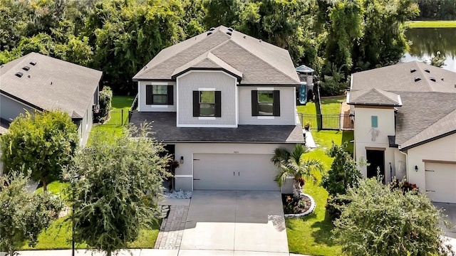 view of front facade with concrete driveway, fence, a front lawn, and a shingled roof