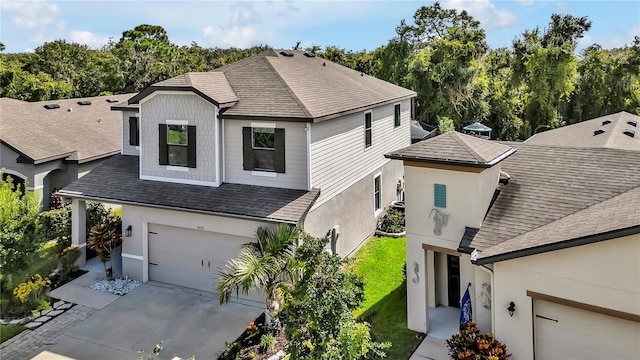 view of front facade with concrete driveway, a shingled roof, a garage, and a front yard