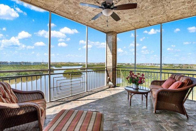 sunroom / solarium featuring a water view, plenty of natural light, and ceiling fan