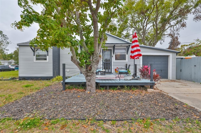 view of front of house with a deck, concrete driveway, an attached garage, and fence