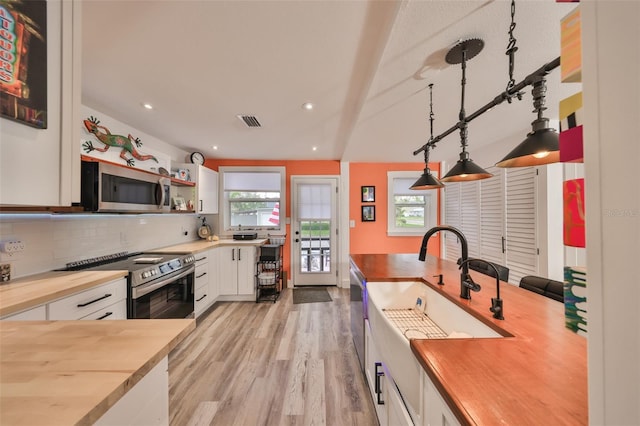 5601 2nd Ave N, Saint Petersburg, FL 33710 - kitchen with butcher block counters, visible vents, white cabinets, appliances with stainless steel finishes, and backsplash
