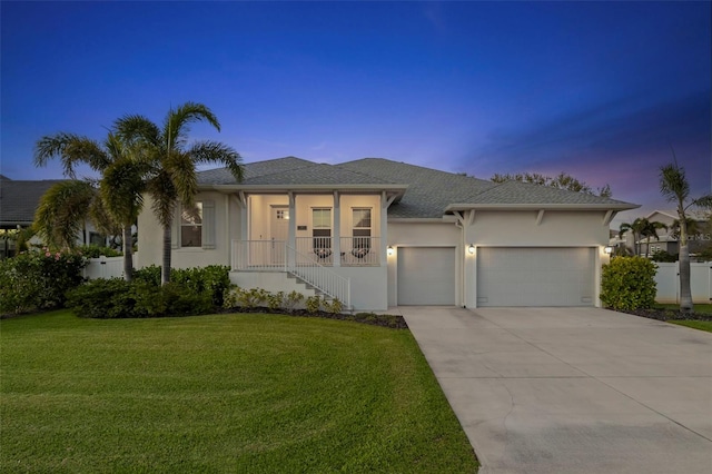 prairie-style home with stucco siding, fence, a garage, driveway, and a front lawn