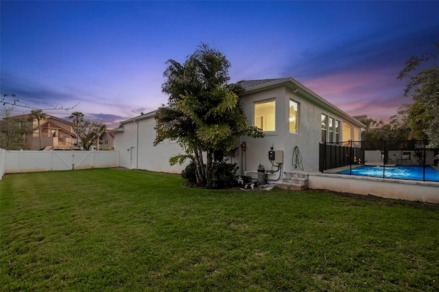 rear view of property with a fenced in pool, a fenced backyard, a lawn, and stucco siding