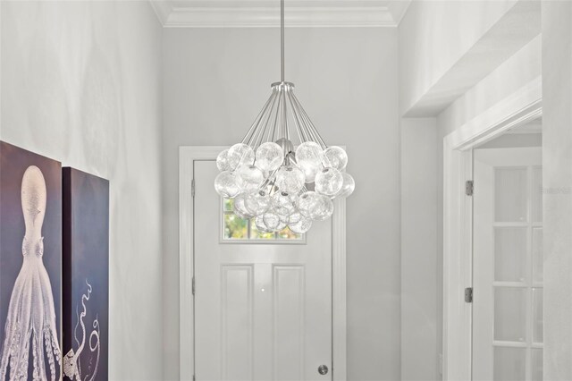 entryway with ornamental molding and a notable chandelier