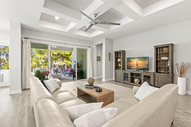 living room with light wood-type flooring, coffered ceiling, plenty of natural light, and baseboards