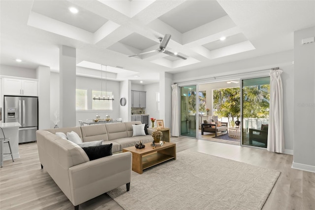 living area featuring light wood-style flooring, coffered ceiling, a wealth of natural light, and baseboards