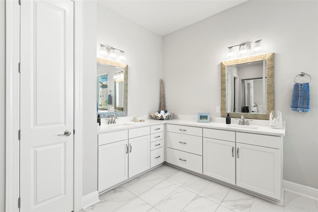 bathroom with marble finish floor, double vanity, and a sink