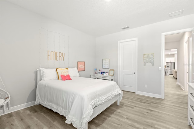 bedroom with light wood-style floors, visible vents, and baseboards