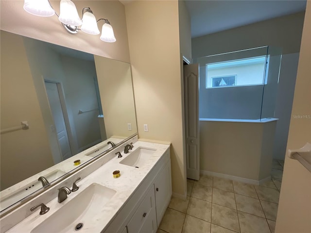 full bathroom with double vanity, tile patterned flooring, a sink, and baseboards