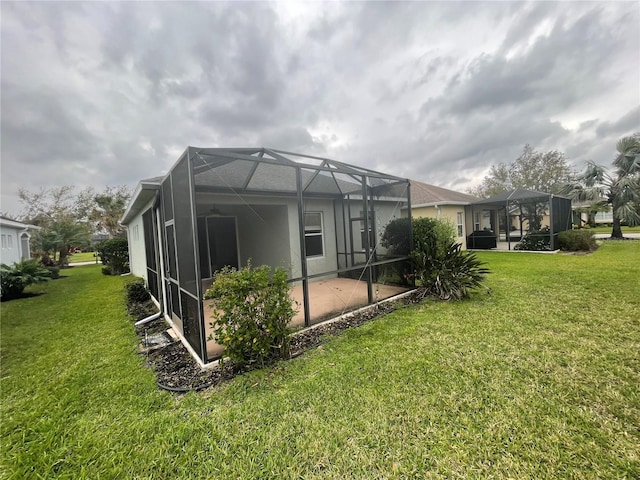 rear view of house with a yard, glass enclosure, a patio, and ceiling fan