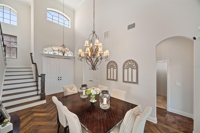 dining room with arched walkways, a high ceiling, stairway, and visible vents