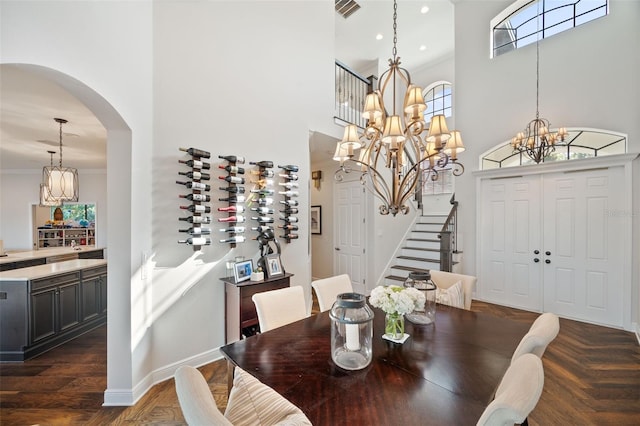 dining space with a towering ceiling, stairs, visible vents, and a notable chandelier