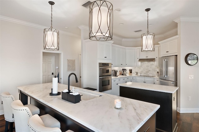 kitchen featuring crown molding, decorative backsplash, appliances with stainless steel finishes, a sink, and an island with sink