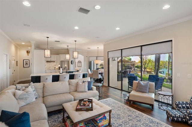 living room with dark wood-style floors, recessed lighting, visible vents, and crown molding