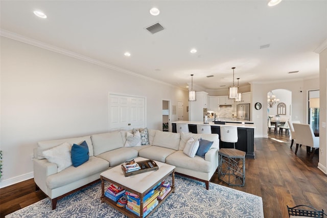 living room featuring arched walkways, dark wood-type flooring, baseboards, and crown molding