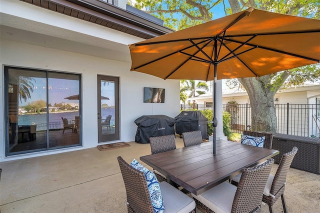 view of patio featuring outdoor dining space, fence, and a grill