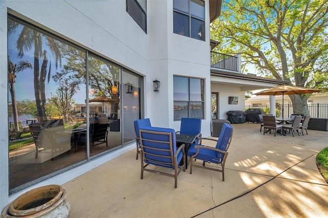 view of patio / terrace featuring a balcony, fence, and outdoor dining space