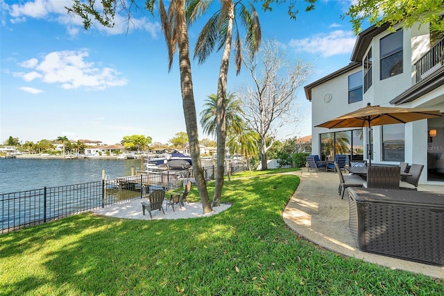 view of yard featuring a patio, a water view, and fence