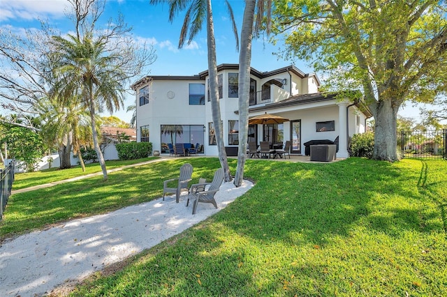 rear view of property with a yard, a patio area, fence, and a balcony