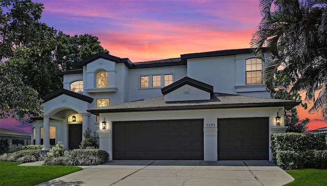 view of front of home featuring a garage, concrete driveway, and stucco siding