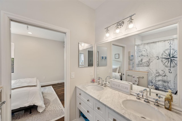 full bathroom with ensuite bathroom, double vanity, wood finished floors, and a sink