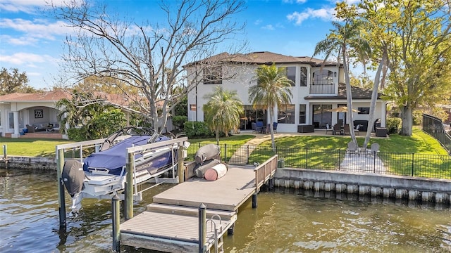 dock area featuring a patio, a lawn, a water view, and a fenced backyard