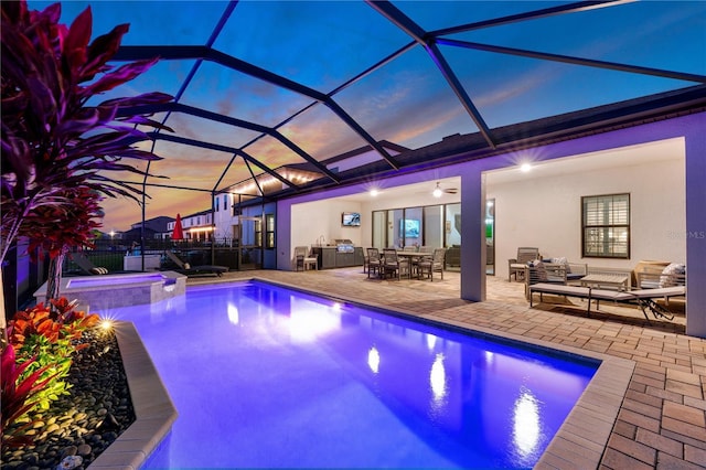 view of pool with outdoor lounge area, a patio area, fence, exterior kitchen, and a lanai