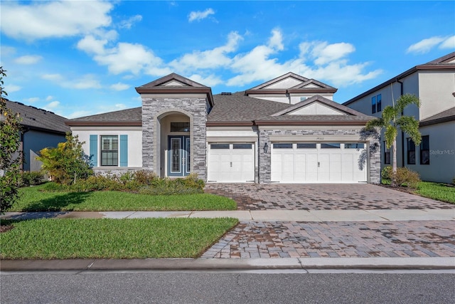 view of front of home with a garage, stone siding, decorative driveway, and stucco siding