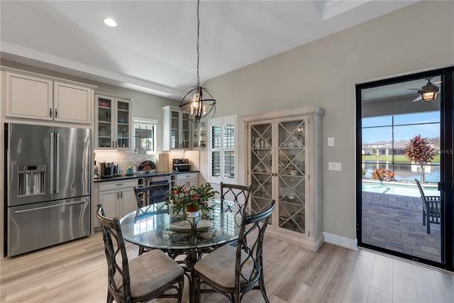 dining space with light wood-type flooring, ceiling fan with notable chandelier, baseboards, and recessed lighting