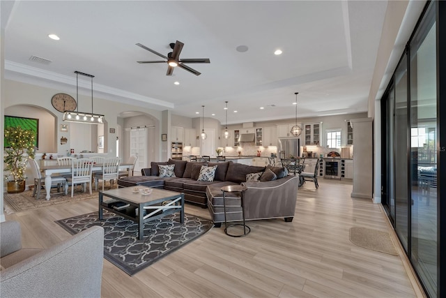 living room featuring arched walkways, recessed lighting, visible vents, a ceiling fan, and light wood-type flooring