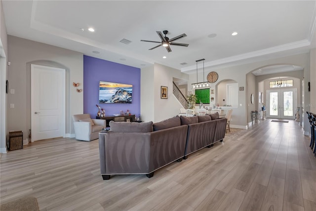 living room with arched walkways, visible vents, stairs, french doors, and light wood finished floors