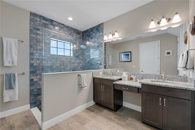 full bath featuring two vanities, a walk in shower, and a sink