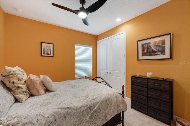 bedroom with a closet, light colored carpet, ceiling fan, and baseboards