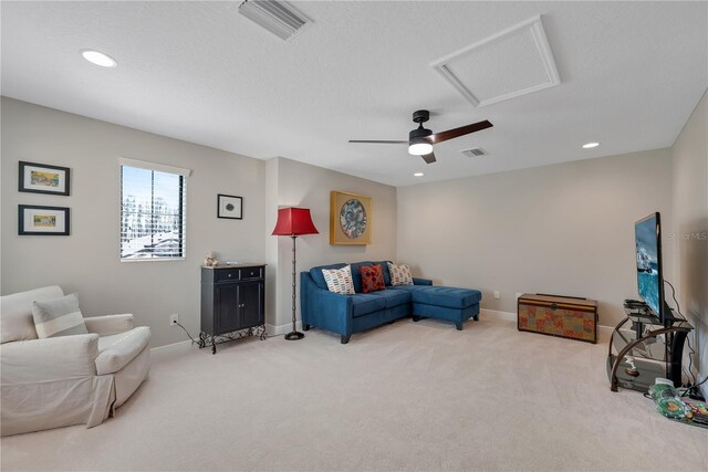 living area with visible vents, light carpet, attic access, and baseboards