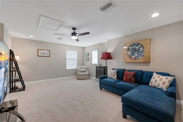 living room featuring attic access, visible vents, baseboards, a textured ceiling, and carpet floors