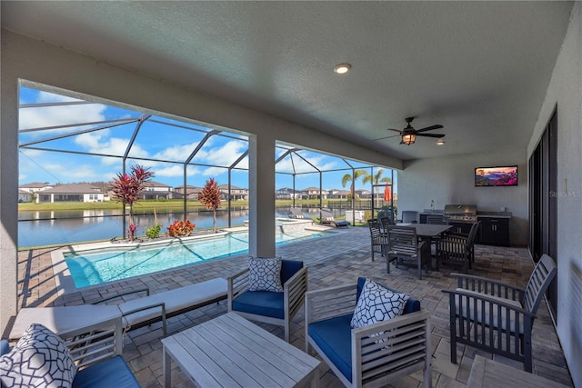 view of patio / terrace featuring an outdoor kitchen, glass enclosure, ceiling fan, a water view, and an outdoor living space