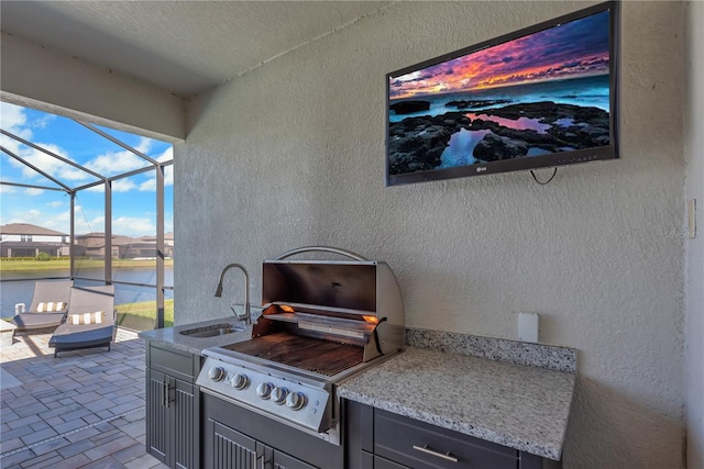 view of patio / terrace with glass enclosure, an outdoor kitchen, area for grilling, a sink, and a water view