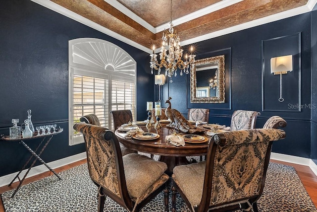 dining area featuring crown molding, a notable chandelier, baseboards, and wood finished floors