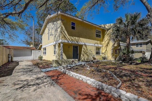 view of front facade featuring a garage, concrete driveway, an outbuilding, and stucco siding