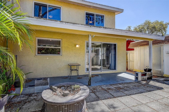 rear view of house featuring a patio, fence, and stucco siding