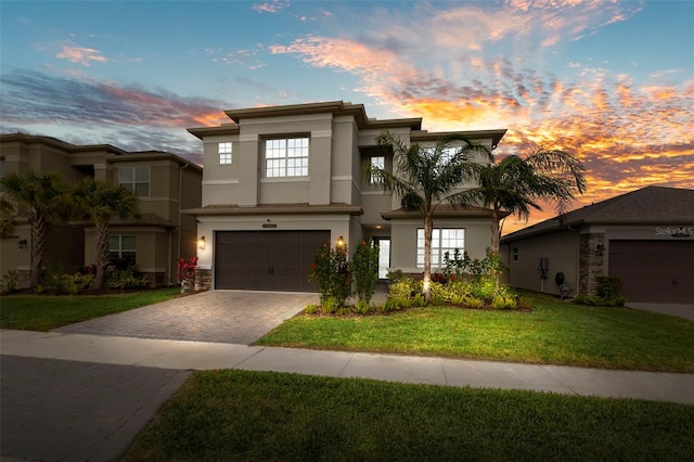 view of front of home with a front lawn, decorative driveway, an attached garage, and stucco siding